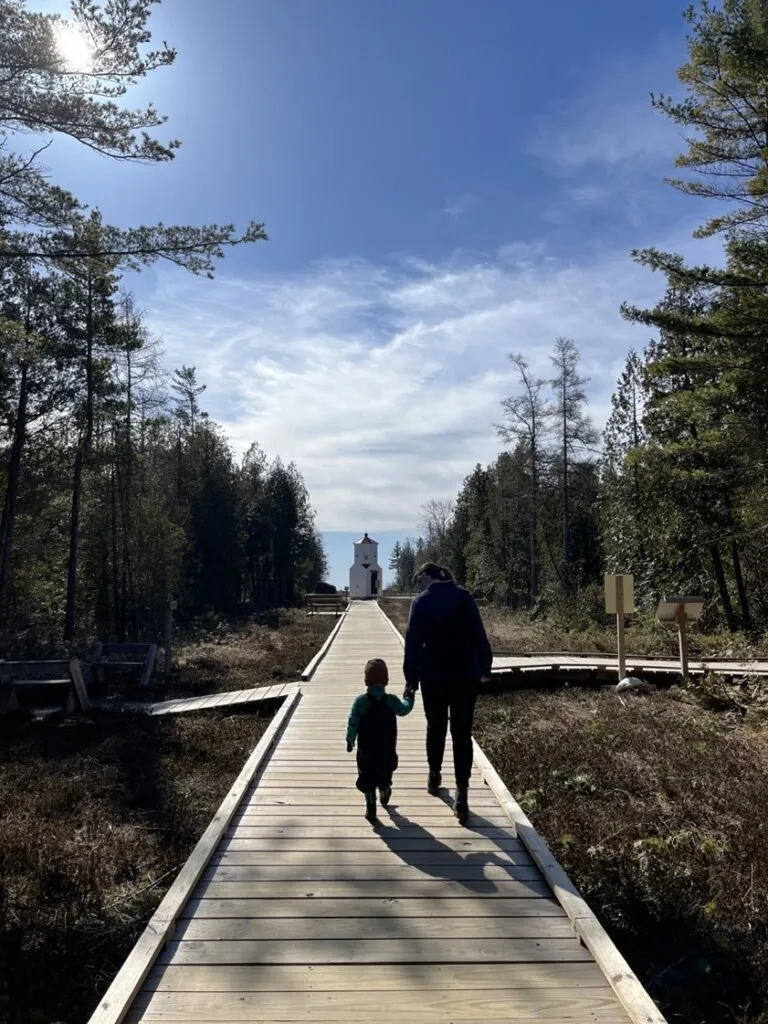 A mom and young son walk down the boardwalk on a sunny day.